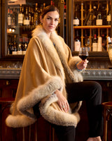 Woman wearing golden island silver fur trimmed cervinia while holding a glass of wine, turned to the side