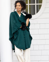 model wearing Volant cashmere ruffled cape in green standing out in front of house