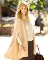model wearing Arden Cashmere Cape in oat, holding a  hand bag
