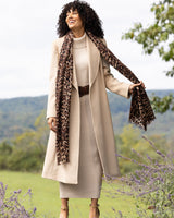 Woman wearing a camel hair Princess Coat in Blonde and leopard print scarf in a scenic outdoor setting