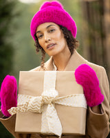 Woman holding a gift and wearing Mink Hat with Fox Fur Pom in Fuchsia
