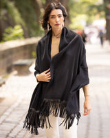 Woman wearing a Cashmere Wrap with Leather Fringe in black on a blurred street background