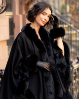 Woman wearing a fur-trimmed coat and Mano fur trimmed leather glove in black in an urban setting