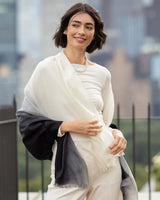 Woman wearing a Lightweight Cashmere Wrap in Black Ombre with a blurred cityscape background