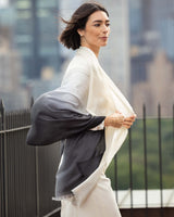 Woman wearing Lightweight Cashmere Wrap in Black Ombre with a cityscape background
