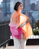 Woman turning around holding and wearing Lightweight Cashmere Wrap in Orange Ombre 