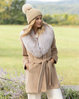 Woman wearing cashmere coat with a fur collar and Montello Ribbed Cashmere Pompom Beanie in Oat
