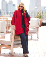 Woman on rooftop wearing sunglasses and volant knit cape in red