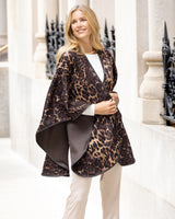 Woman wearing Roma Wild Reversible Cashmere Cape in Leopard Camel/Brown in an urban setting