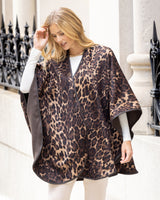 Woman wearing Roma Wild Reversible Cashmere Cape in Leopard Camel/Brown in an urban setting