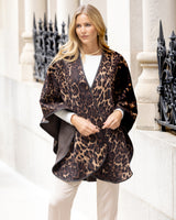 Woman wearing Roma Wild Reversible Cashmere Cape in Leopard Camel/Brown in an urban setting