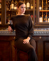 Model holding a glass of wine while wearing Stella Sequin Boat Neck Sweater in black