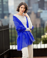 Woman wearing St Tropez lightweight cashmere wrap in  Cobalt with a cityscape background