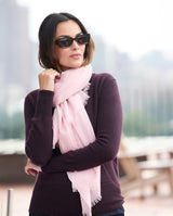 Model wearing St Tropez wrap tied in pink with a sweater, jeans and sunglasses