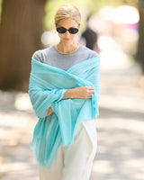 A woman outdoors wearing a turquoise sheer wrap draped over her shoulders.