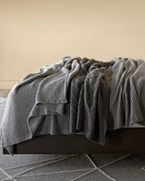 several Umbria cashmere throws on bed in Grey