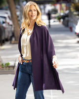 Woman wearing a Voyage Cashmere Wrap in Currant and jeans on a city street.