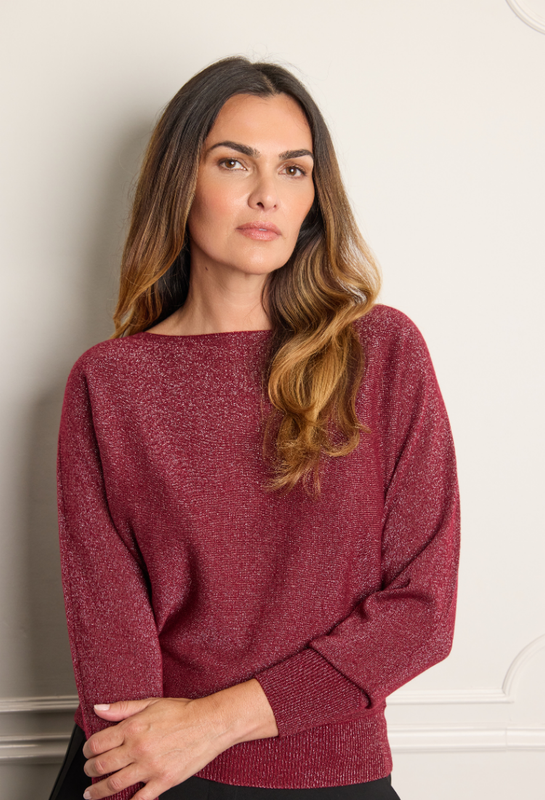 Model standing against a wall in a burgundy sparkly cashmere sweater